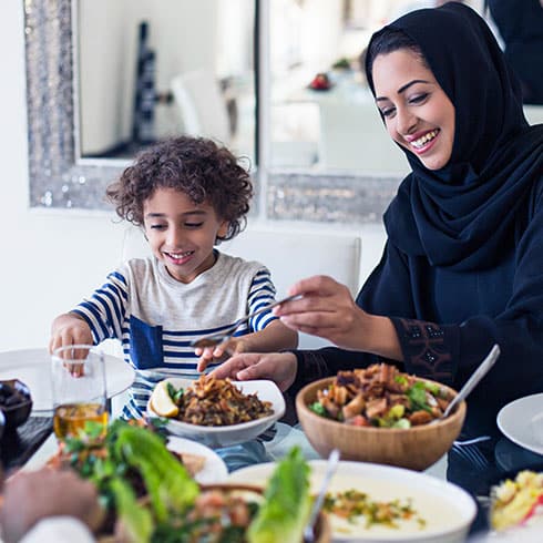 a mother and a son sitting at a dining table eating