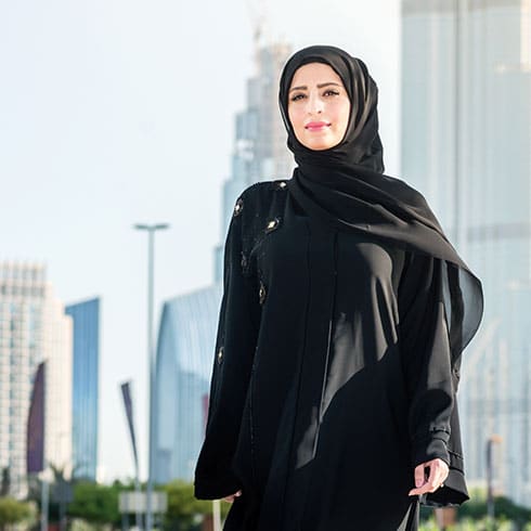 a woman in a hijab stands in a city